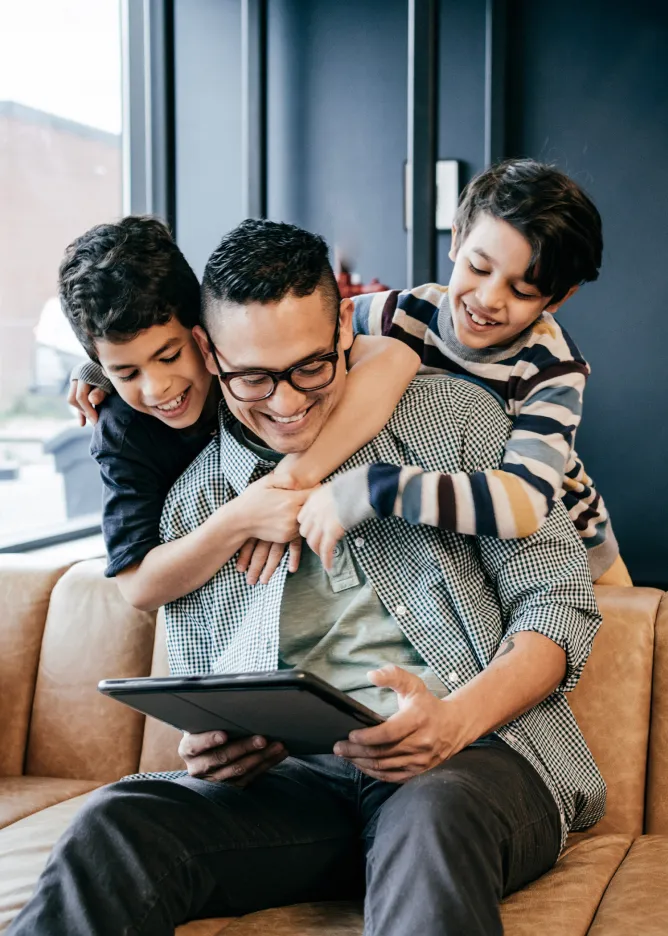Father and two young kids looking at tablet